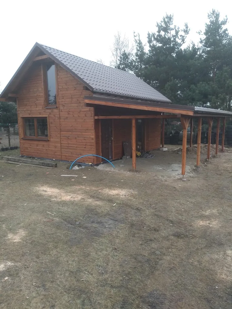 Dom drewniany z zadaszoną wiatą i pokryciem dachówką